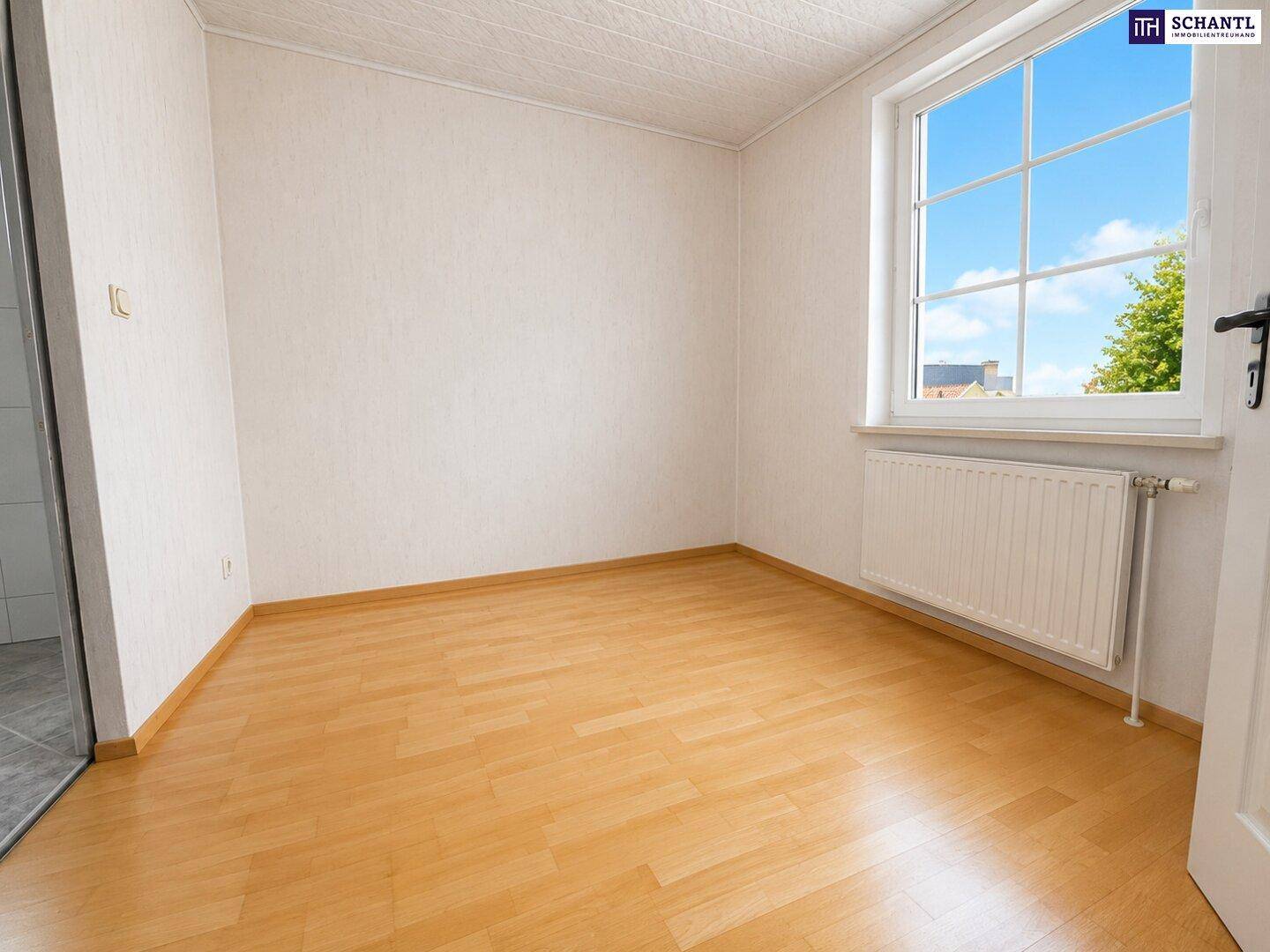 Kleines, helles Zimmer mit Laminatboden und einem Fenster, das viel Tageslicht hereinlässt.