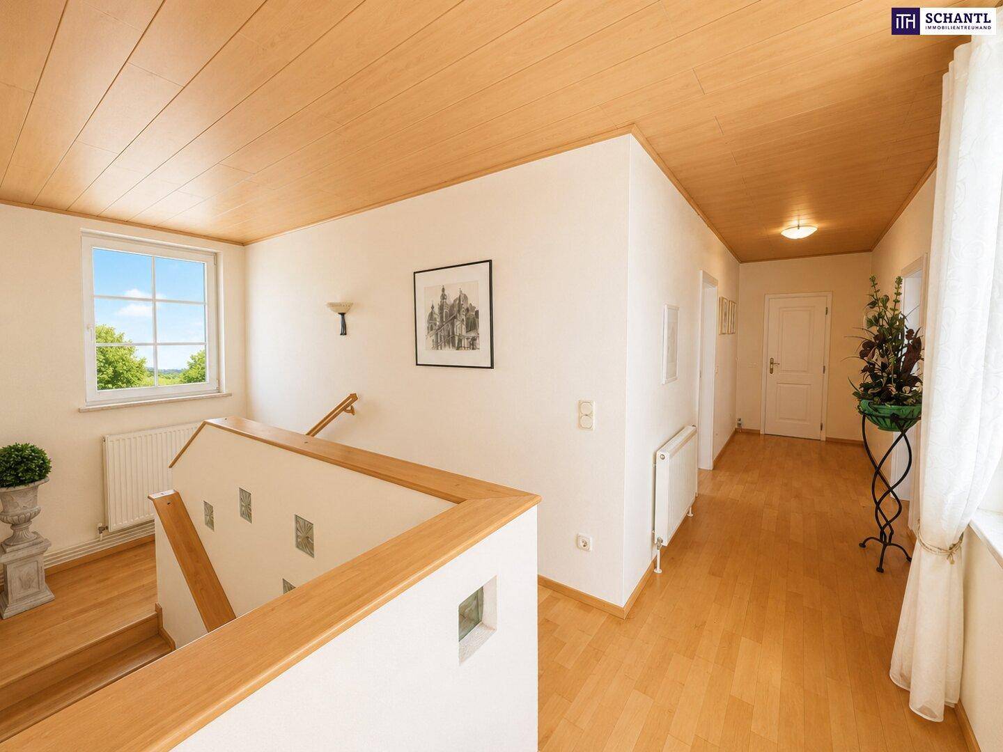 Heller Flur mit Holzdeckenverkleidung, Laminatboden und Treppenaufgang, der zu weiteren Räumen führt.