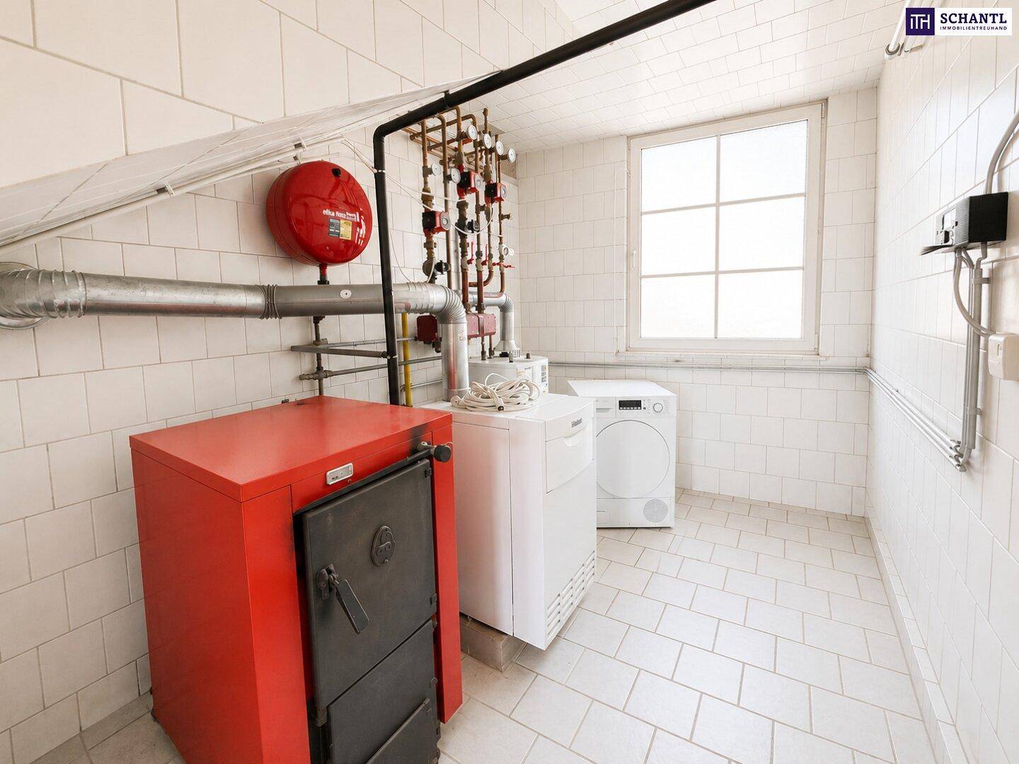 Hauswirtschaftsraum mit Heizungsanlage, Waschmaschine und Trockner, gefliestem Boden und Fenster.
