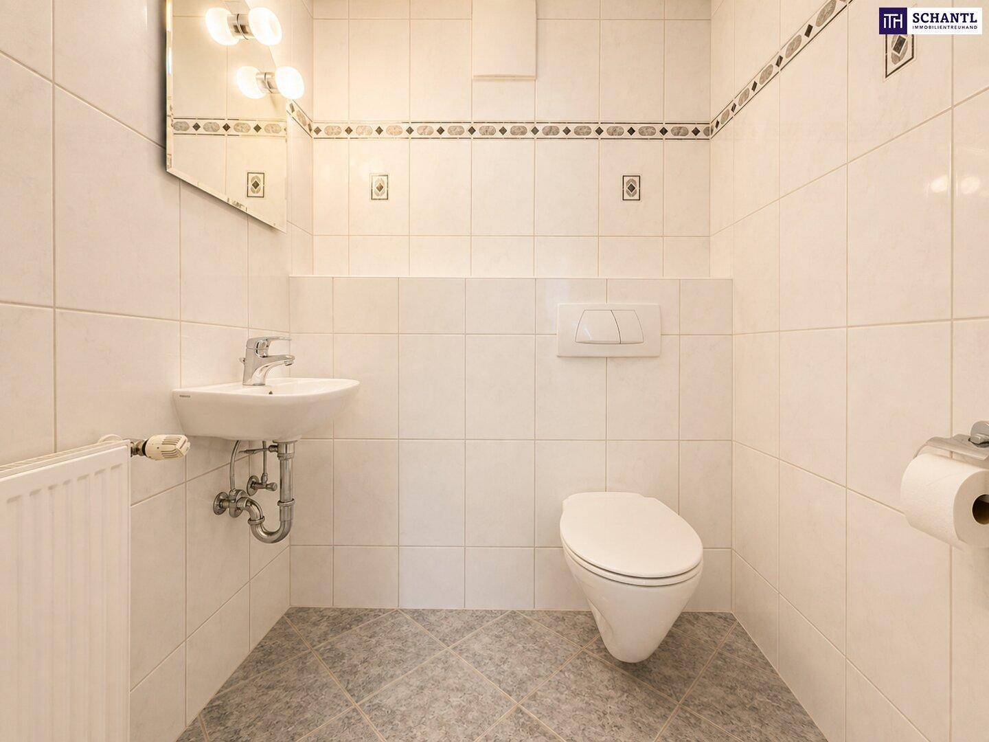 Kleines Gäste-WC mit weißen Wandfliesen, Waschbecken und wandhängender Toilette.