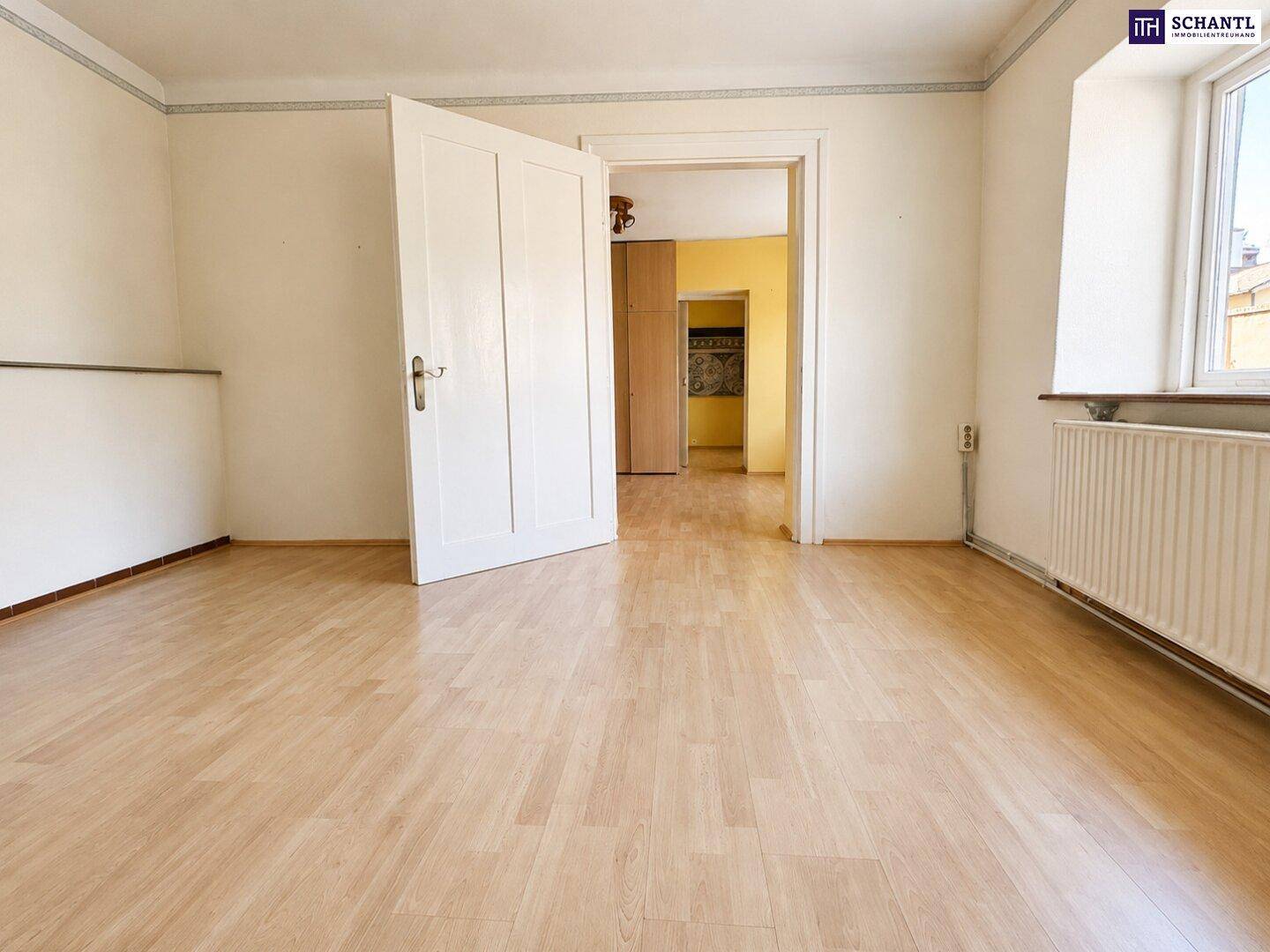 Heller Durchgangsraum mit Laminatboden und offener Tür zu einem weiteren Zimmer.