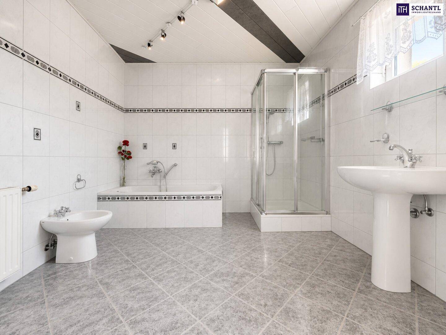 Geräumiges Badezimmer mit weißen Fliesen, Badewanne, Duschkabine und Bidet.