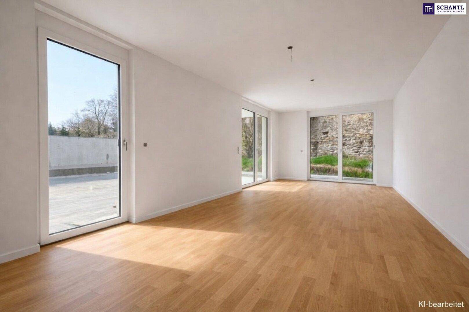 Heller, leerer Raum mit großen Fenstertüren, hellem Parkettboden und weiß gestrichenen Wänden.