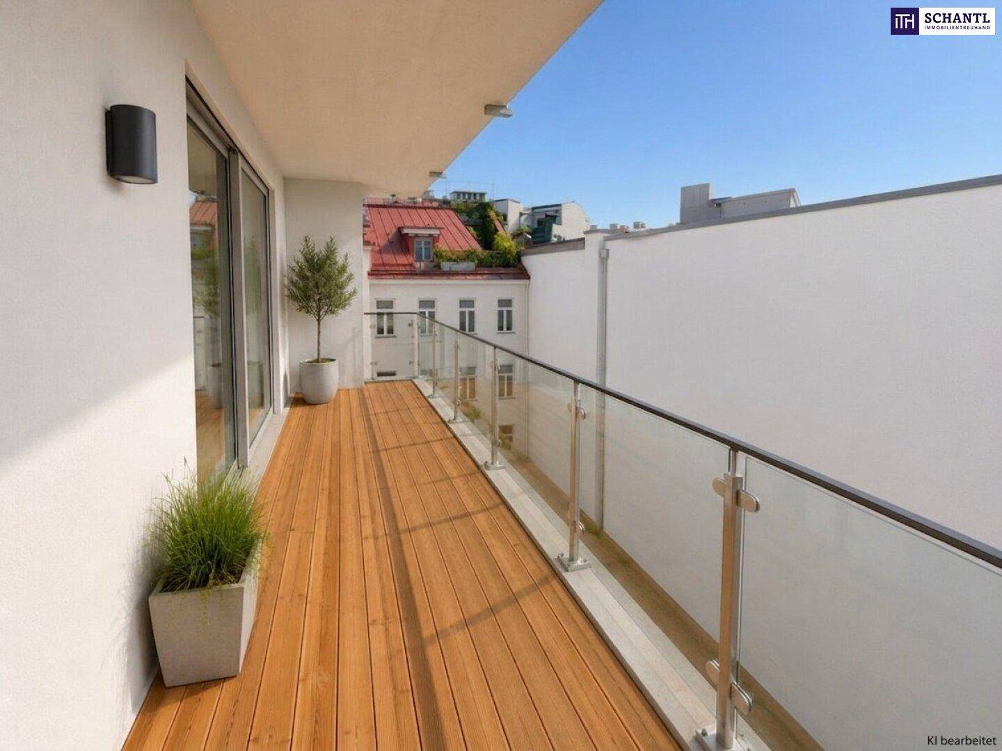 Langer Balkon mit Holzfußboden, Glasgeländer und Blick auf die umliegenden Gebäude.