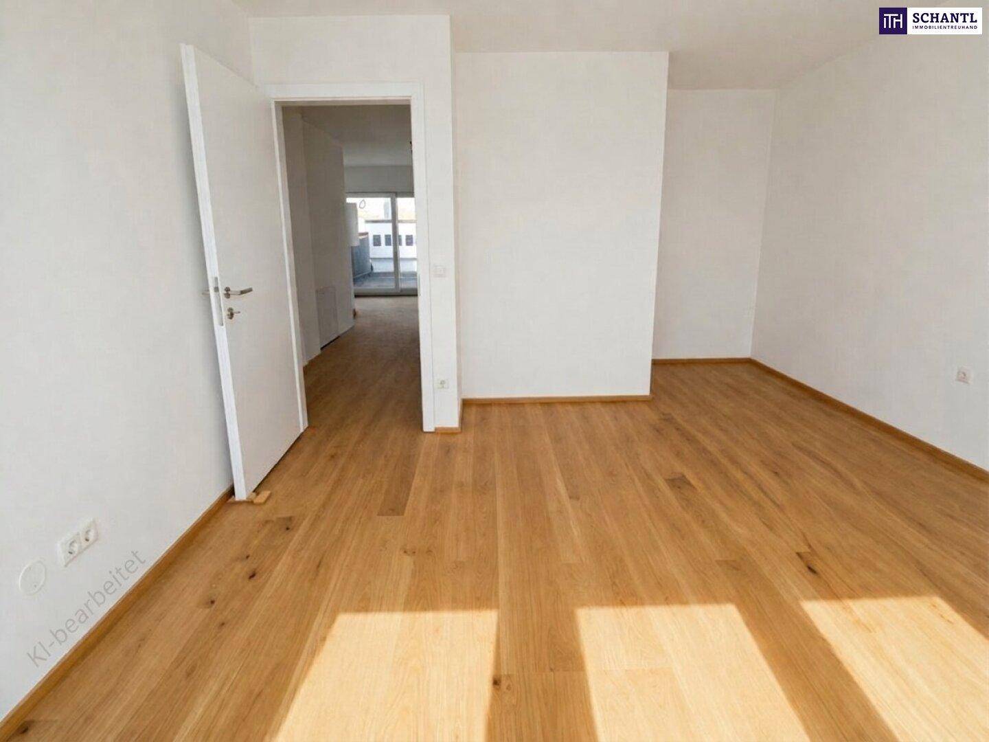 Leerer Innenraum mit hellem Holzfußboden und weißen Wänden, der einen offenen Übergang zu einem weiteren Bereich bietet.
