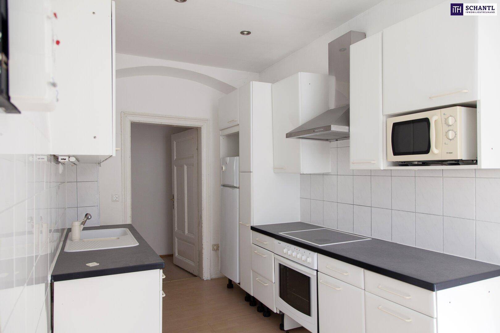Moderne Küche mit weißen Schränken, dunkler Arbeitsplatte und integrierten Geräten.