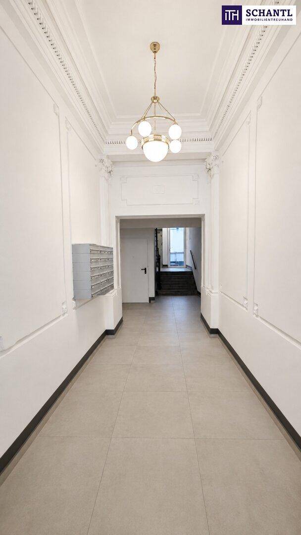 Eleganter Eingangsbereich mit hohen Decken, Stuckverzierungen und einem modernen Kronleuchter.