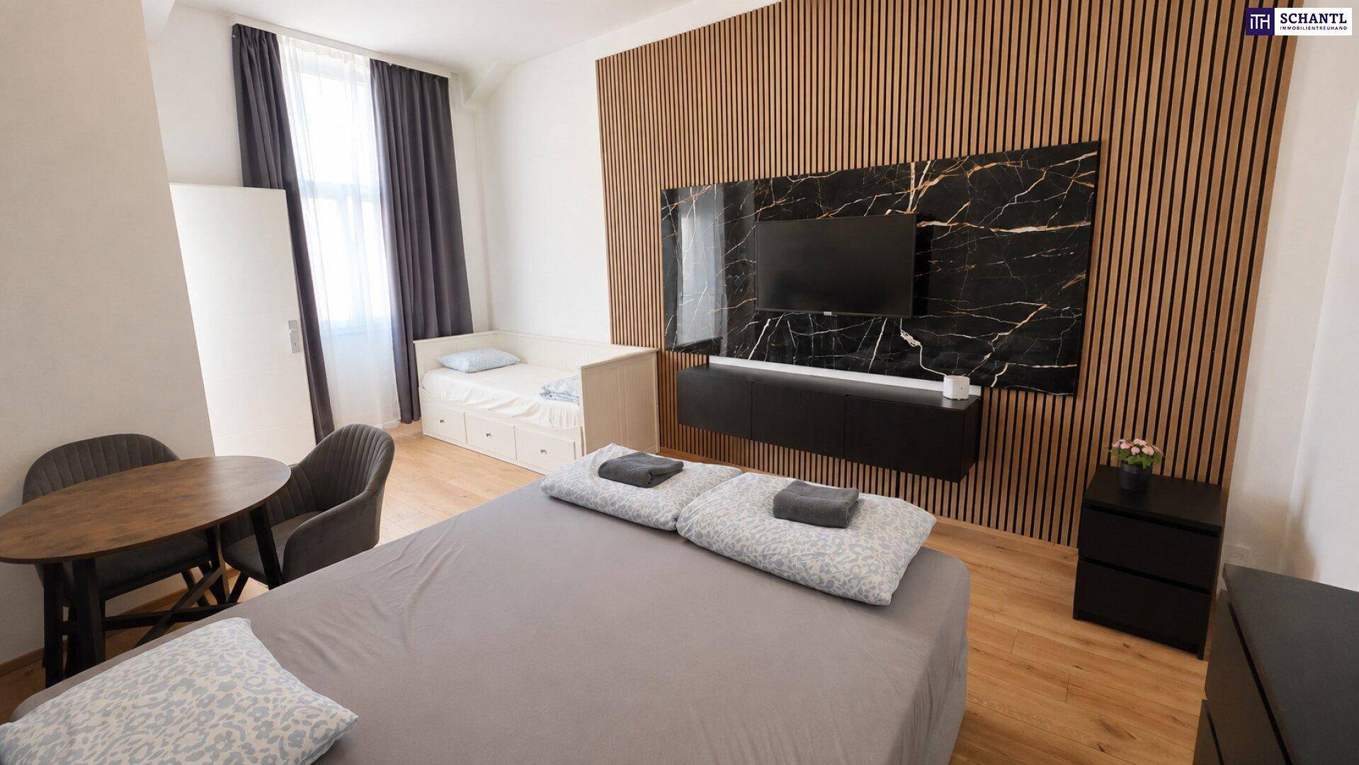 Gemütliches Schlafzimmer mit Holzboden, einem Doppelbett und einem kleinen Esstisch neben dem Fenster.