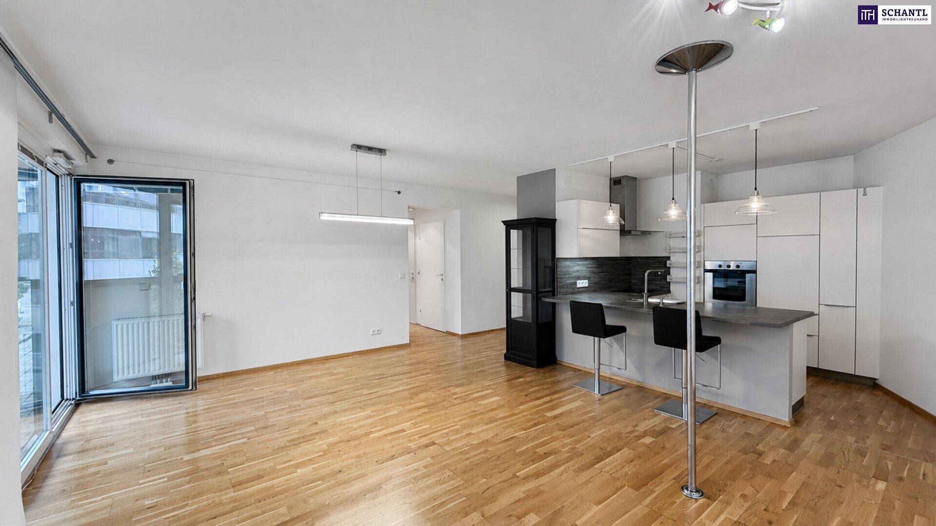 Heller offener Wohnbereich mit moderner Küche, Holzboden und Zugang zum Balkon.