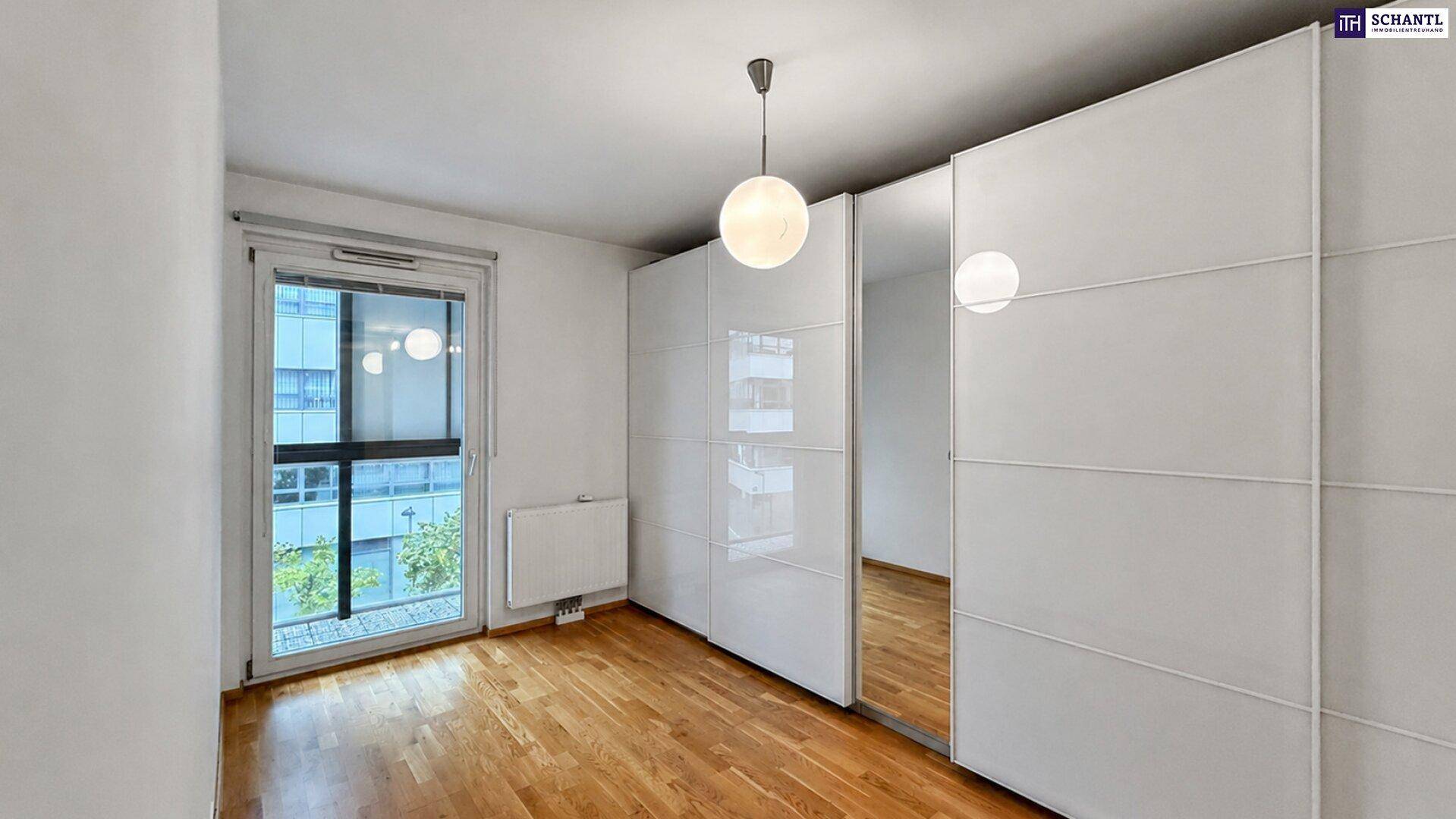 Schlafzimmer mit weißen Einbauschränken, Spiegeltüren und Zugang zum Balkon.