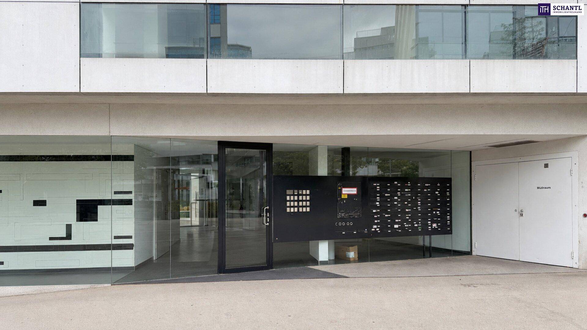 Moderner Gebäudeeingang mit Glasfassade und Briefkastenanlage.