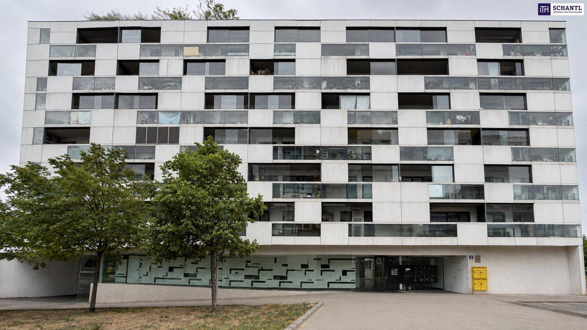 Moderne Fassade eines Mehrfamilienhauses mit vielen Fenstern und Balkonen.