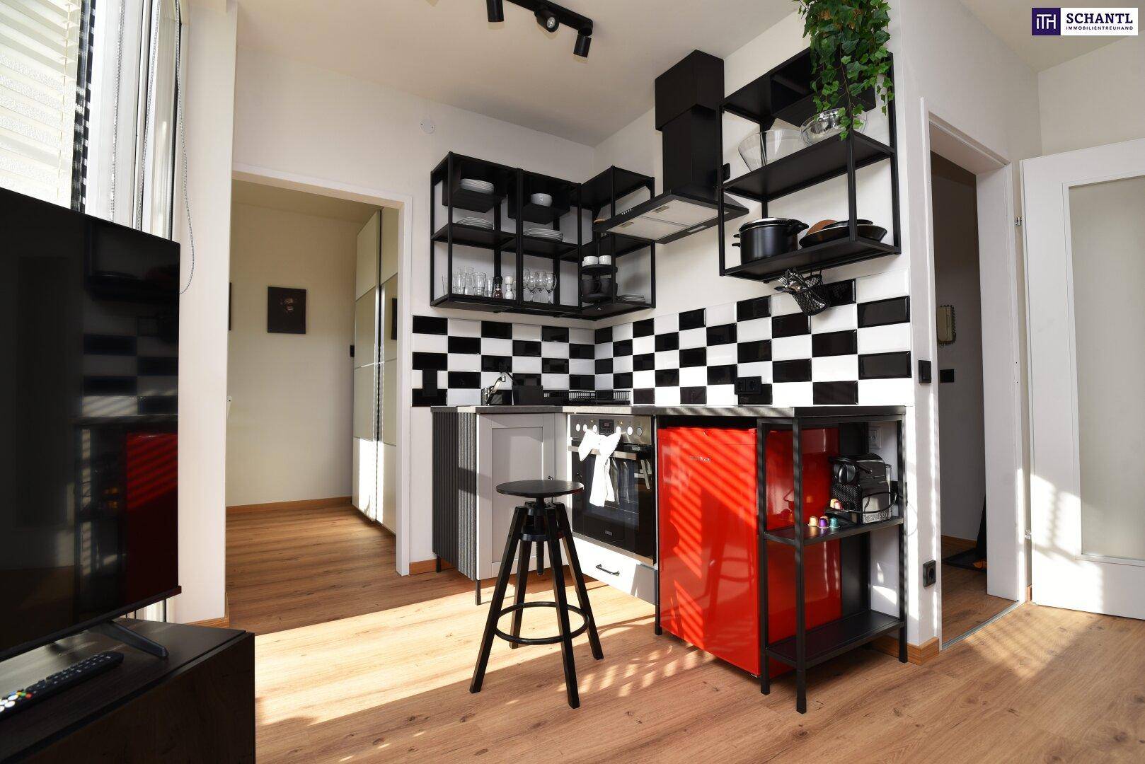 Moderne Küchenzeile mit schwarz-weiß karierten Fliesen, offenen Regalen und einem roten Kühlschrank.