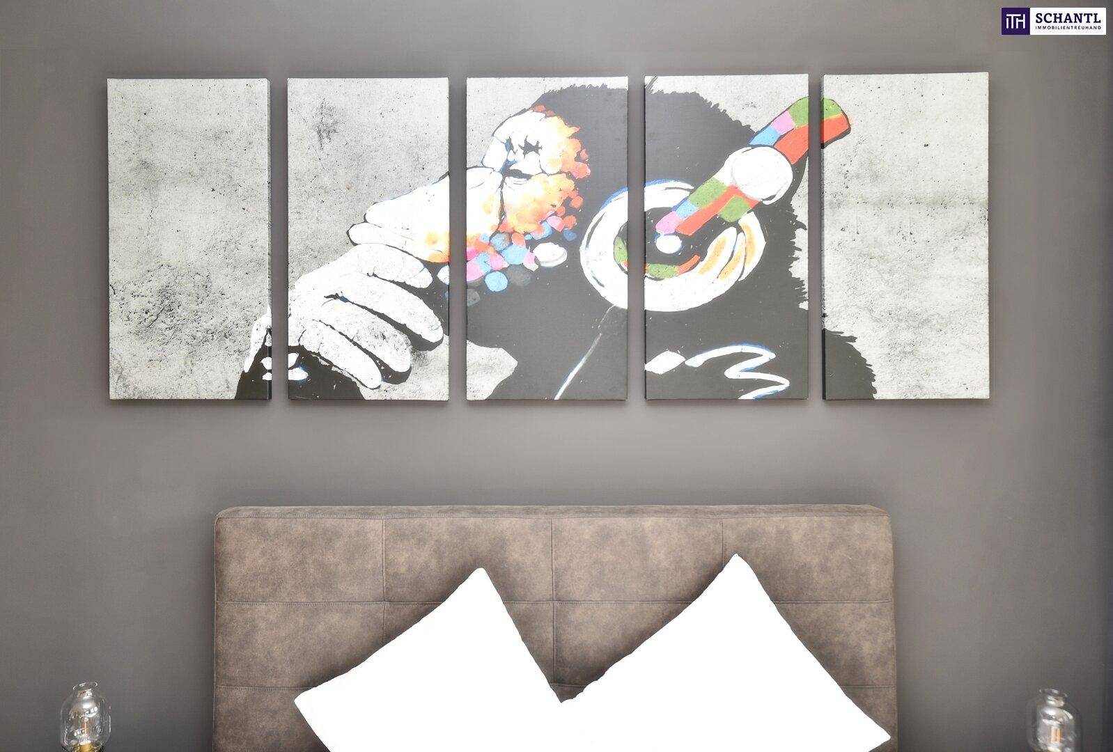 Detailansicht des Bettes mit Kopfteil und moderner Kunst an der dunklen Wand.