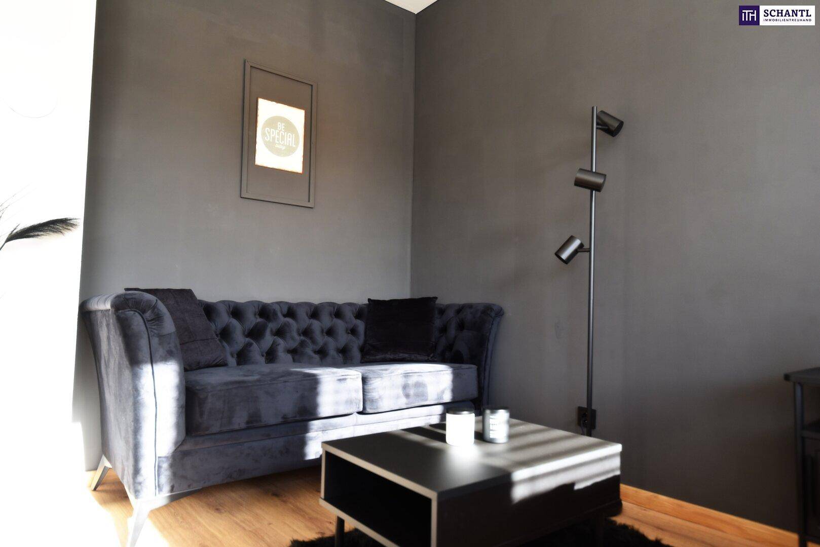 Gemütliche Sitzecke mit einem dunklen Sofa, Couchtisch und einer modernen Stehlampe.