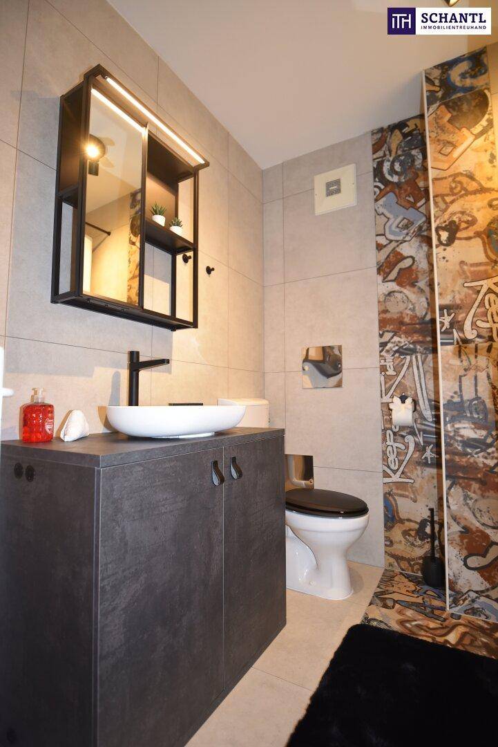 Modernes Badezimmer mit grauen Fliesen, Waschbecken, WC und einer Duschwand mit Muster.