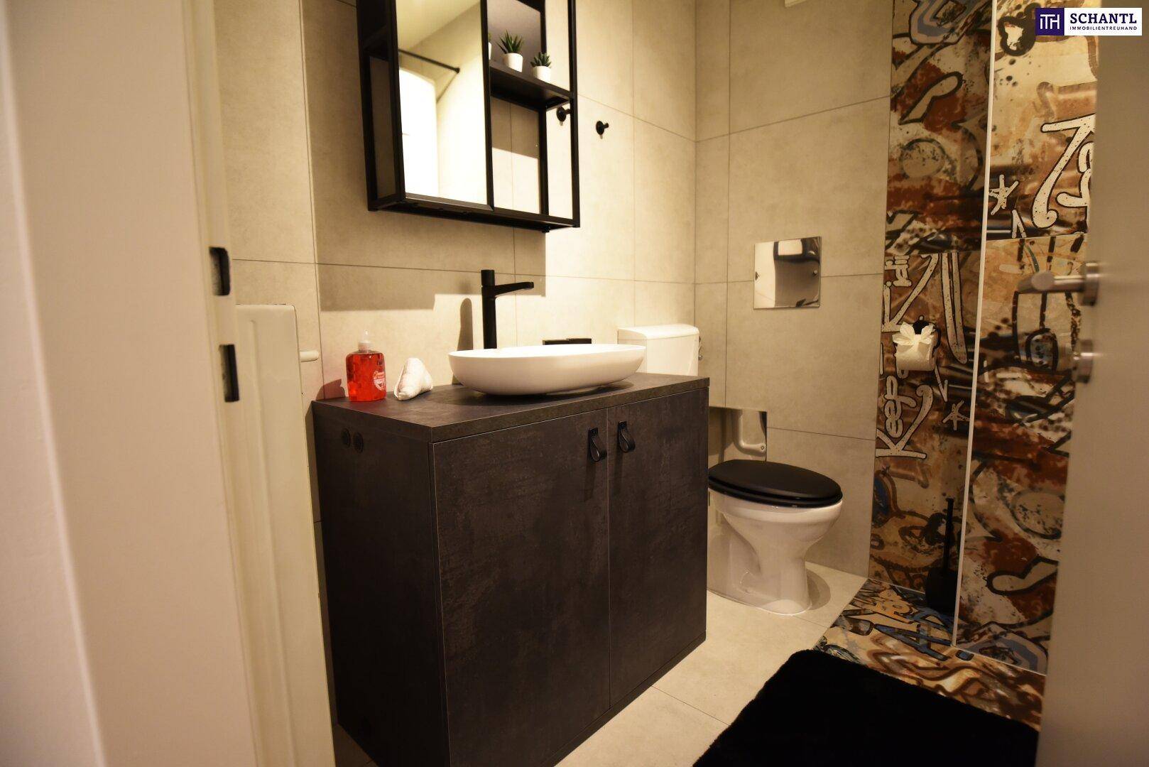 Modernes Badezimmer mit grauen Fliesen, Waschbecken auf Unterschrank und WC.
