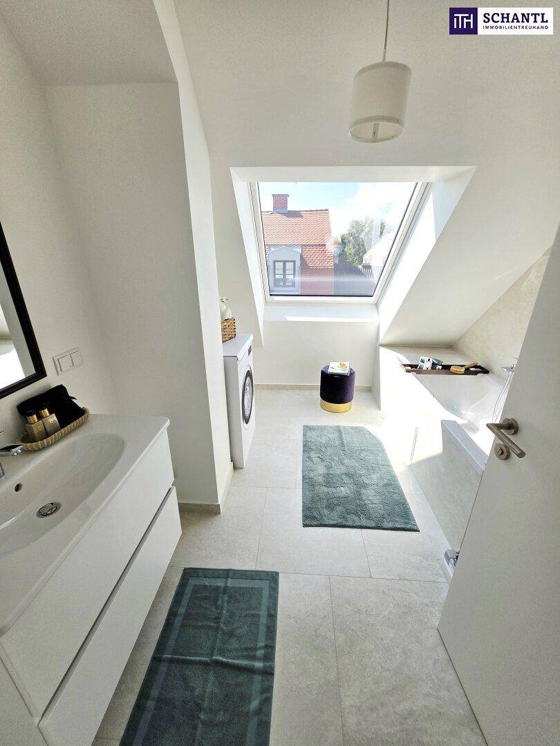 Modernes Badezimmer im Dachgeschoss mit Badewanne, Waschmaschine und Dachfenster.