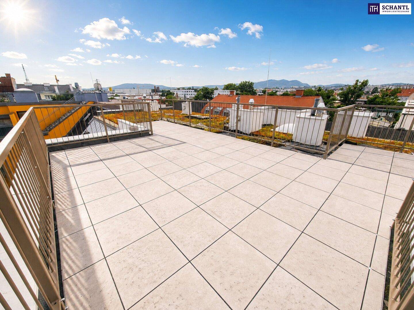 Weitläufige Dachterrasse mit Fliesenboden und Panoramablick über die Stadt und die Berge.