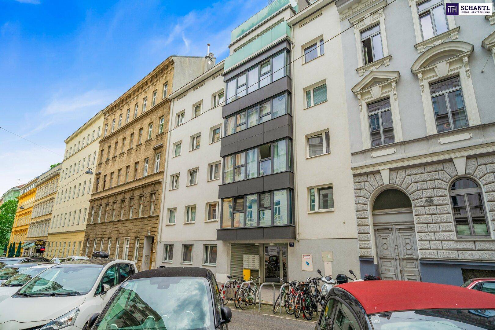 Fassade eines Mehrfamilienhauses in einer städtischen Umgebung mit geparkten Autos.