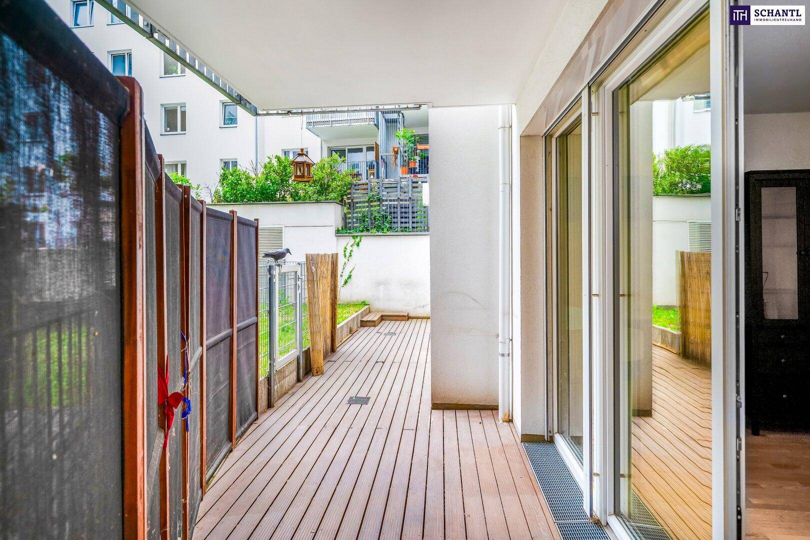 Geräumige Terrasse mit Holzdeck und Zugang zu einem kleinen privaten Gartenbereich.