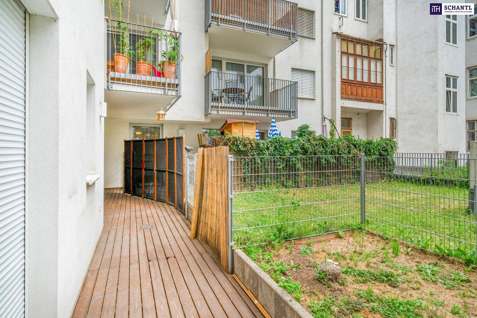 Außenbereich mit Holzterrasse und angrenzendem Garten, umgeben von Wohngebäuden.