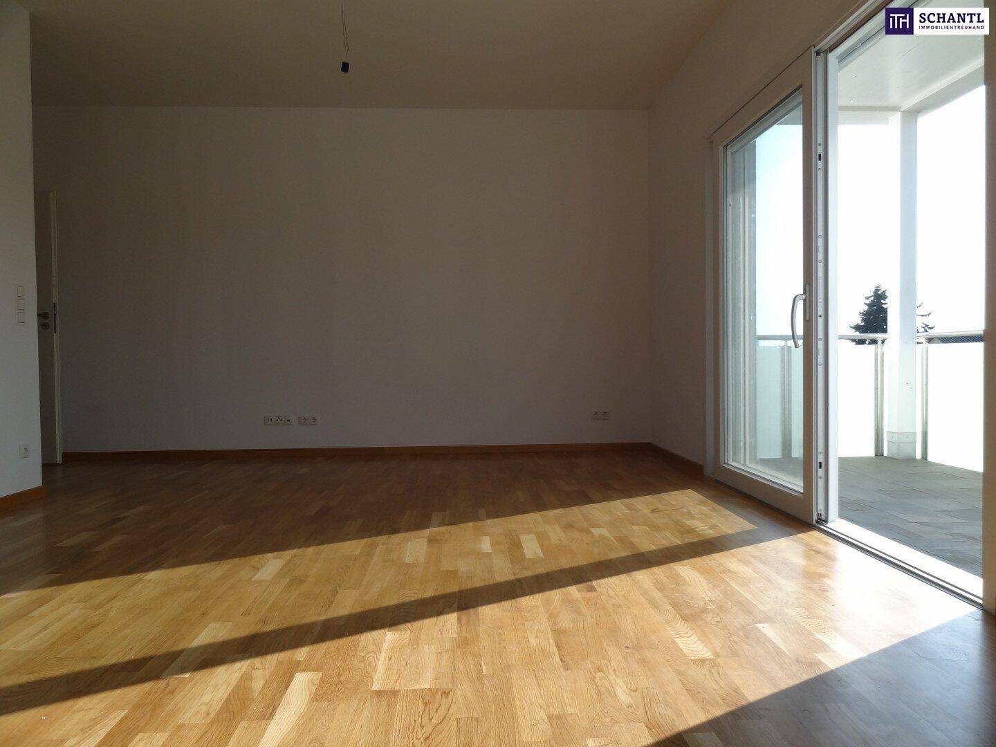 Lichtdurchfluteter Raum mit Holzboden und breitem Zugang zu einem sonnigen Balkon.