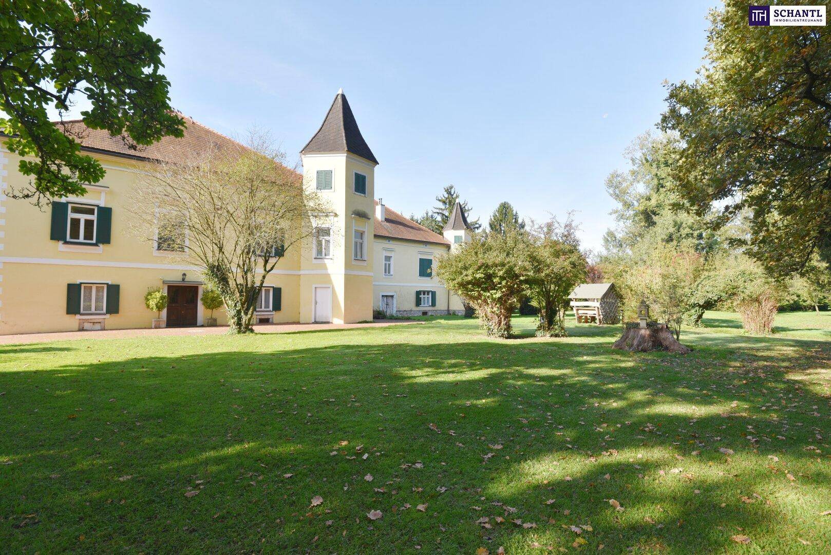 Weitläufiger Gartenbereich mit gepflegtem Rasen und altem Baumbestand vor dem historischen Gebäude.