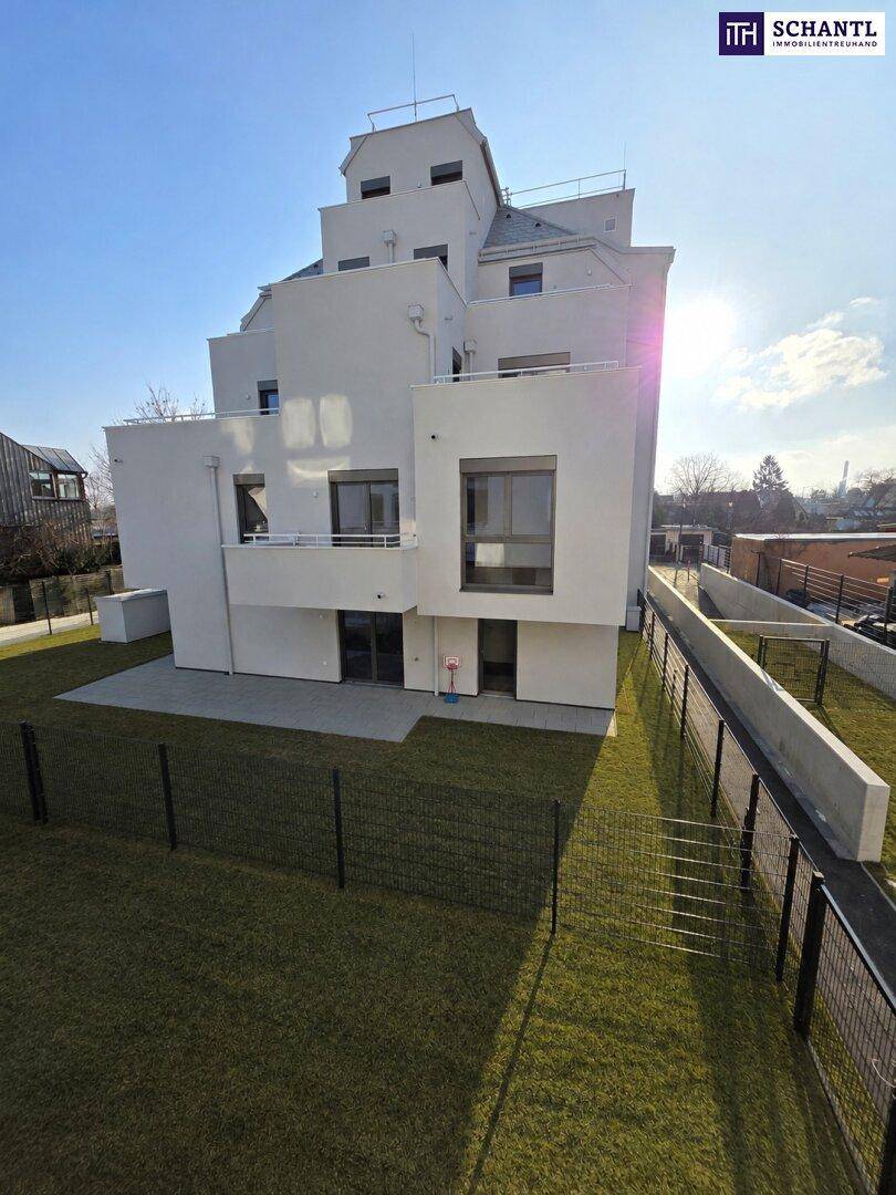 Moderne weiße Fassade eines Neubaus mit Terrassenbereich und privatem Garten.