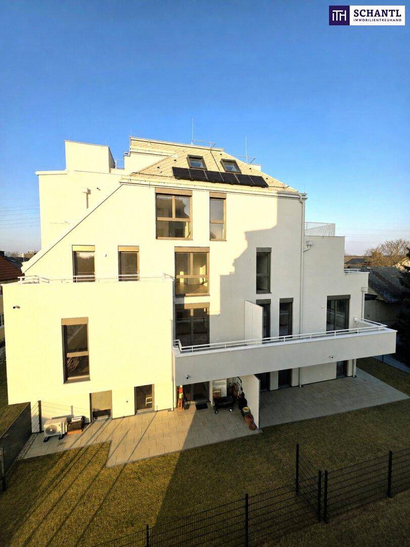 Ansicht der modernen Gebäudefassade mit großen Fenstern und Solarpaneelen auf dem Dach.