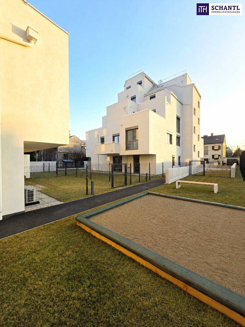 Außenbereich des Wohnkomplexes mit Sandkasten und Rasenfläche, ideal für Kinder.