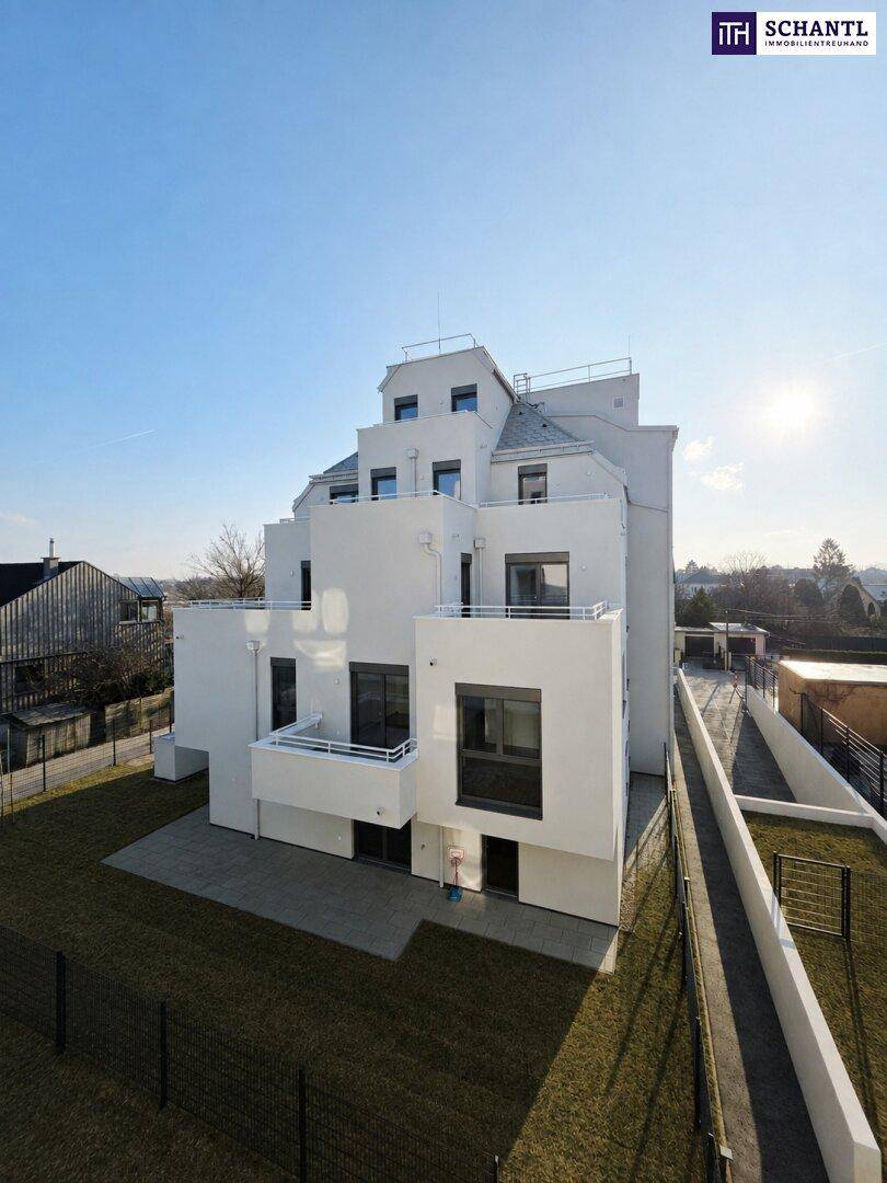 Moderne, gestufte Architektur eines weißen Mehrfamilienhauses mit Balkonen und Grünflächen.