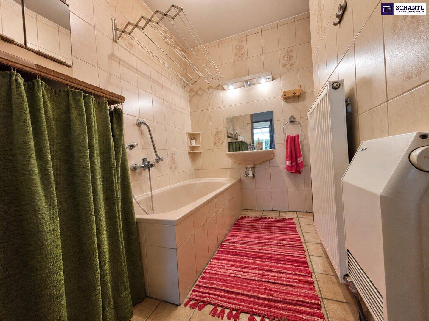Gefliestes Badezimmer mit Badewanne, Duschvorhang und Heizkörper, in traditionellem Stil.