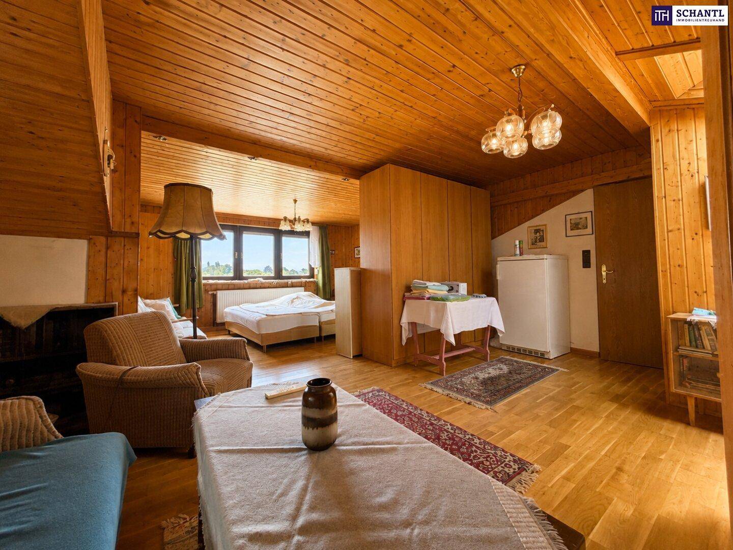 Großer Raum mit Holzvertäfelung an Wänden und Decke, bietet viel Platz zum Wohnen und Schlafen.