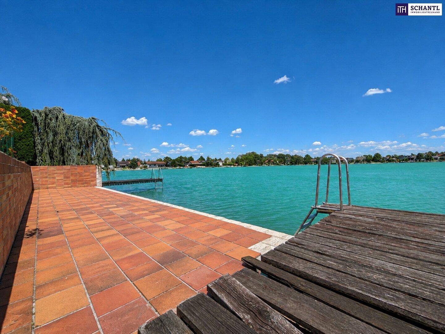 Geräumige Terrasse mit Fliesenboden und Holzsteg direkt am Seeufer, ideal zum Entspannen.