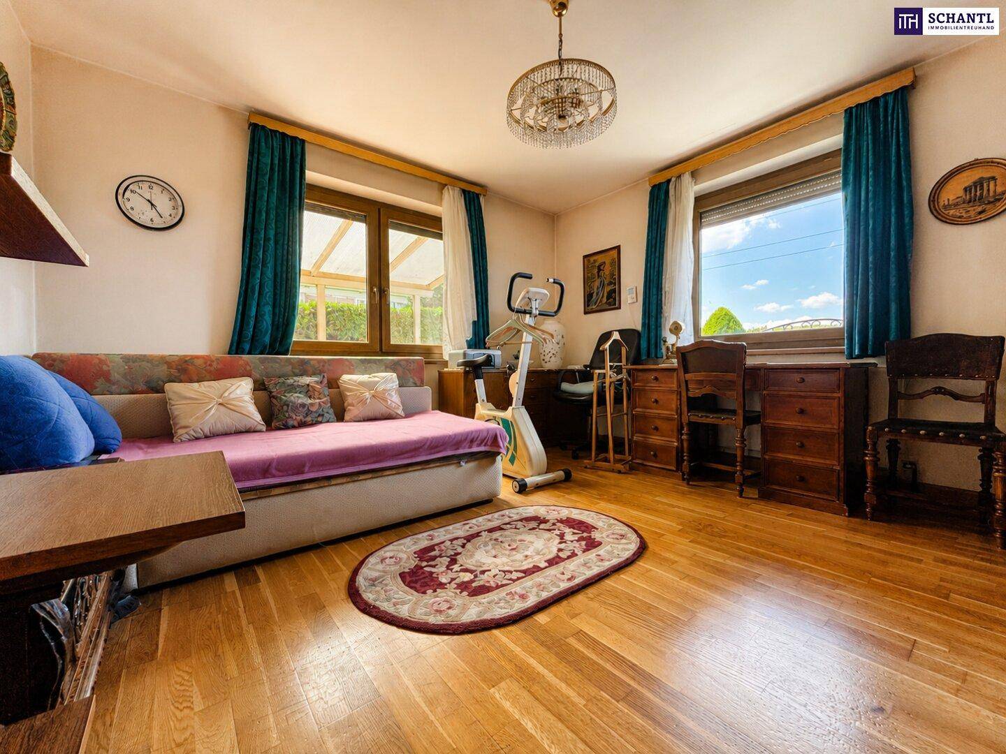 Gemütliches Schlafzimmer mit Parkettboden, zwei Fenstern und einem Heimtrainer für sportliche Aktivitäten.