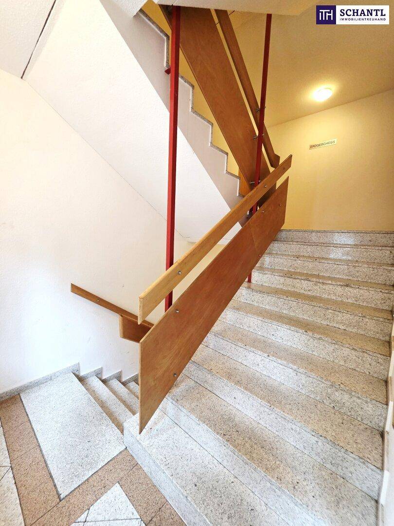 Treppenhaus mit Steinstufen und Holzgeländer, das verschiedene Etagen des Gebäudes verbindet.