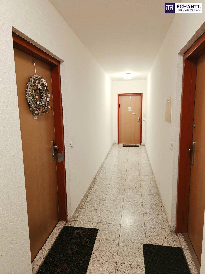 Langer, heller Flur mit Fliesenboden und mehreren Türen, der zu den Zimmern führt.