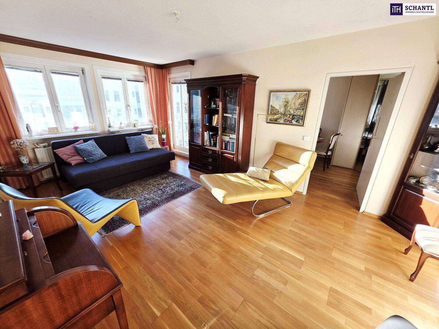 Gemütliches Wohnzimmer mit Parkettboden, bequemen Möbeln und viel Tageslicht durch große Fenster.