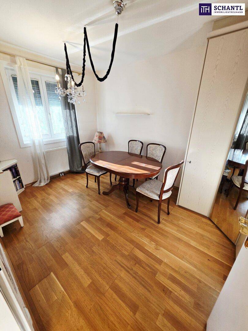 Esszimmer mit Holztisch, passenden Stühlen und Parkettboden, beleuchtet von einem Kronleuchter.