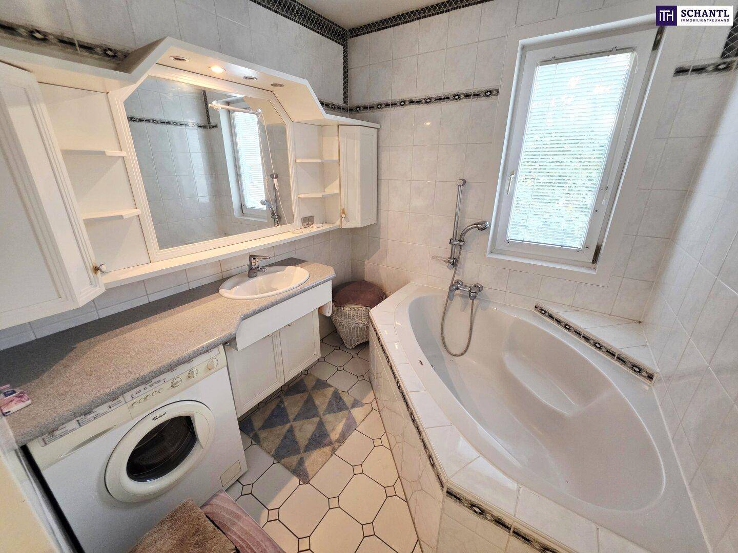 Badezimmer mit Badewanne, Waschbecken, Spiegelschrank und Fenster, gefliest in Weiß.
