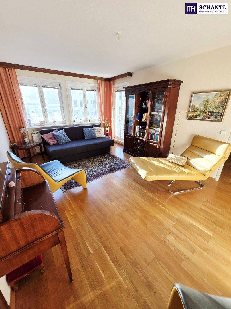 Wohnzimmer mit Parkettboden, bequemen Sitzmöbeln und großen Fenstern für viel Tageslicht.