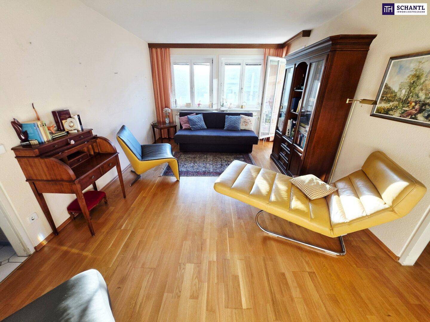 Helles Wohnzimmer mit Holzboden, klassischer Einrichtung und Zugang zu einem Außenbereich.