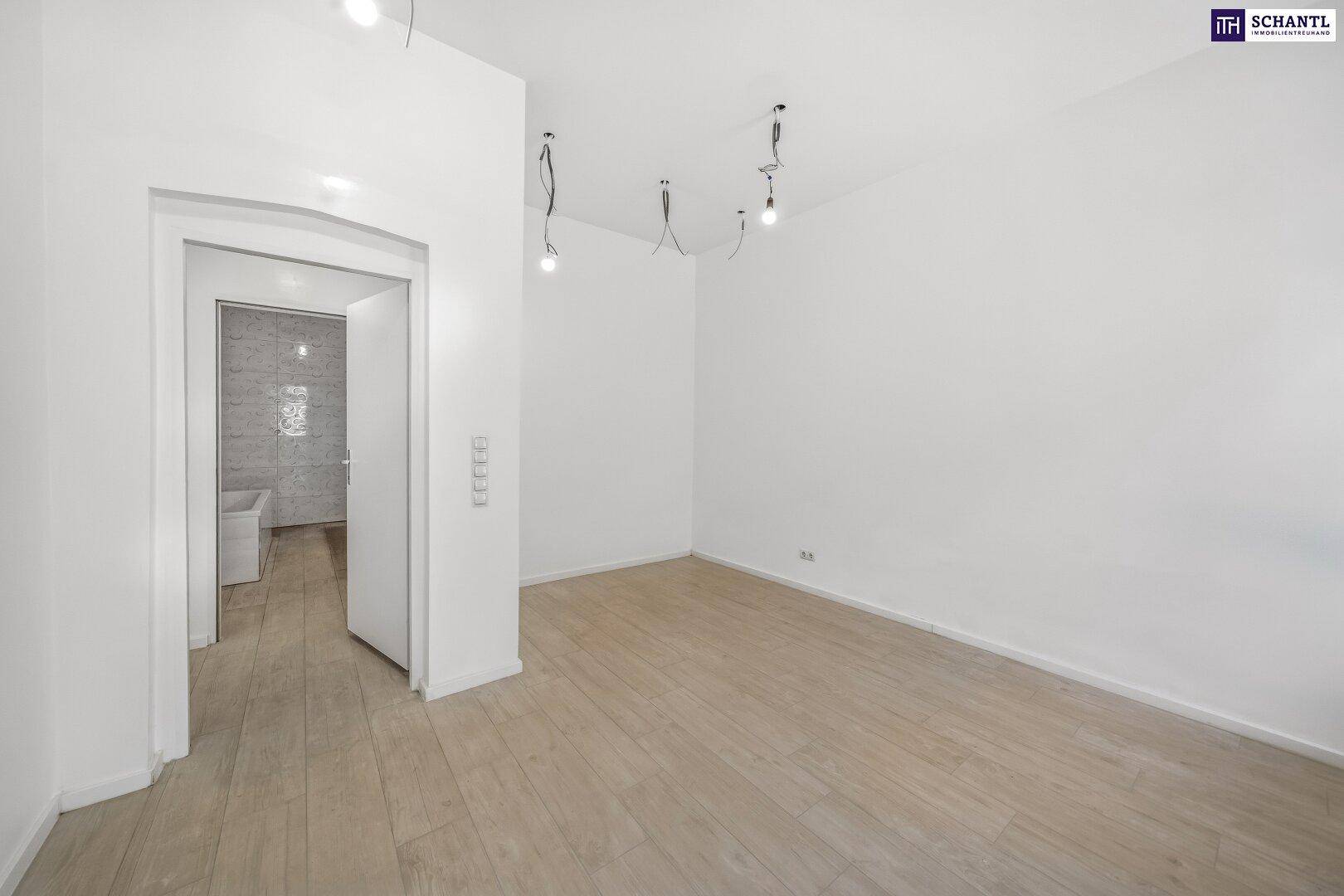 Leeres Schlafzimmer mit hellem Holzfußboden und Zugang zu einem modernen Badezimmer, unmöbliert.