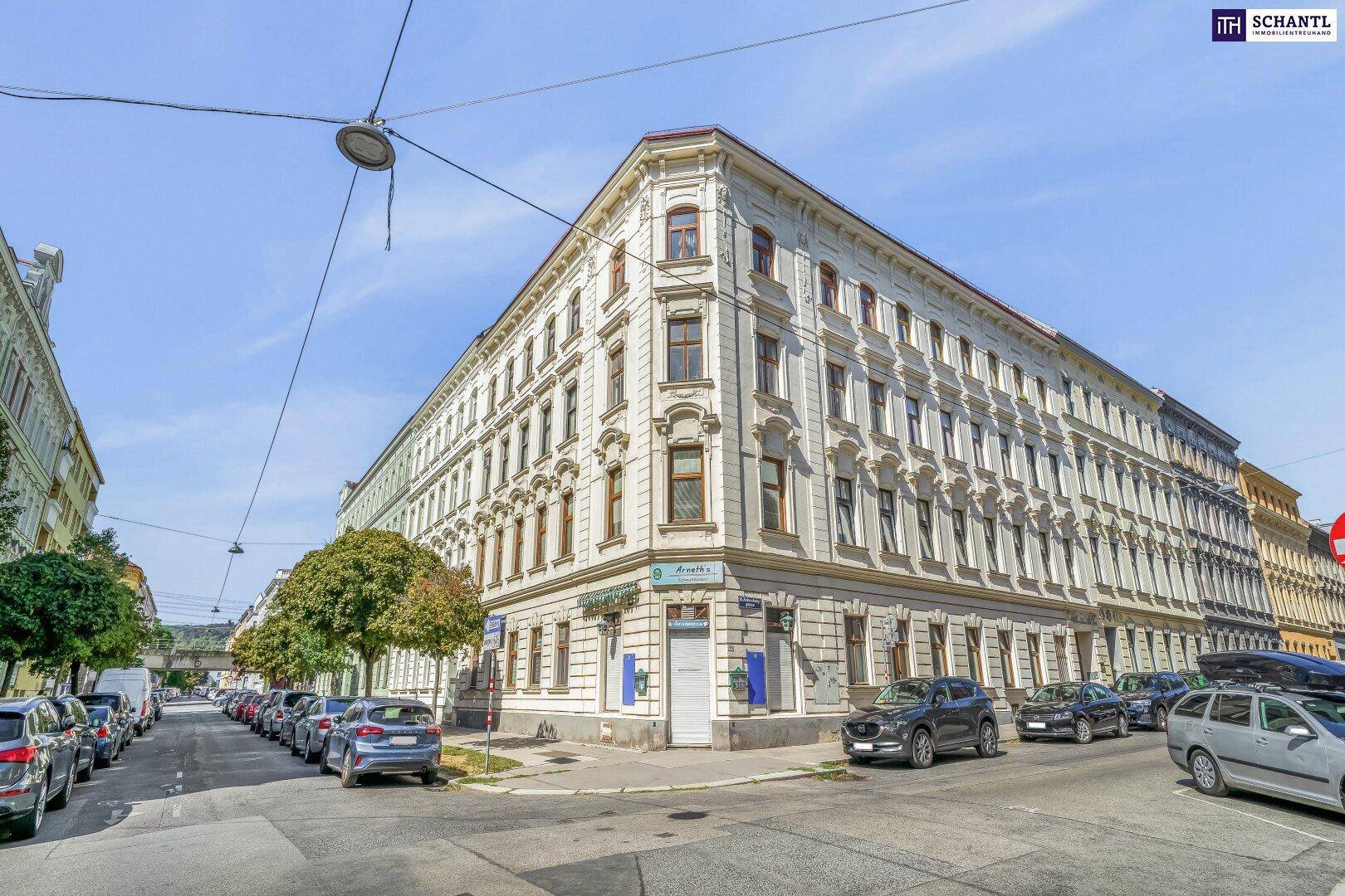 Historisches Eckgebäude in der Stadt mit klassischer Architektur und vielen Fenstern, umgeben von Parkplätzen.