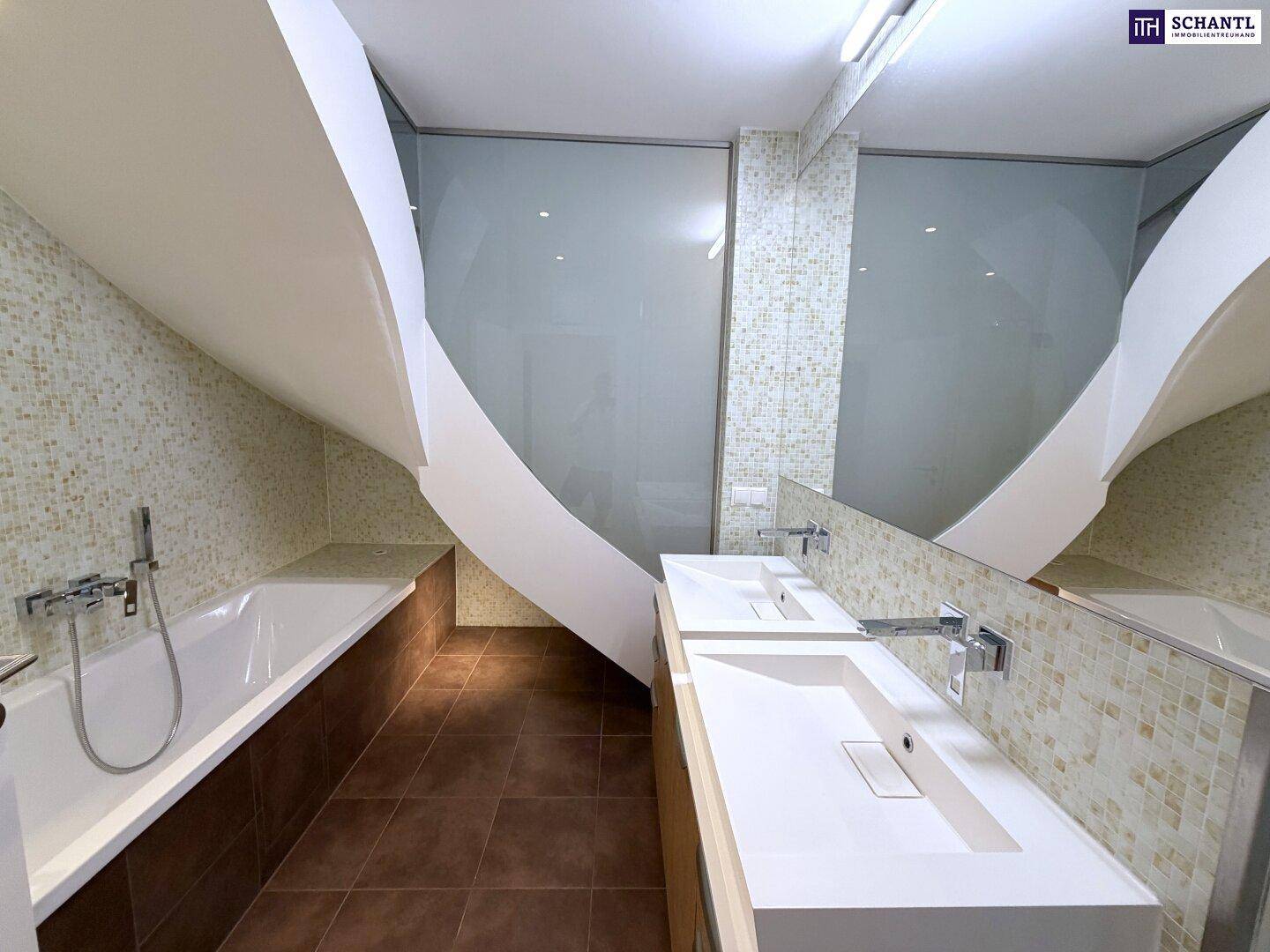 Modernes Badezimmer mit Doppelwaschbecken, Badewanne und Mosaikfliesen unter einer Dachschräge.