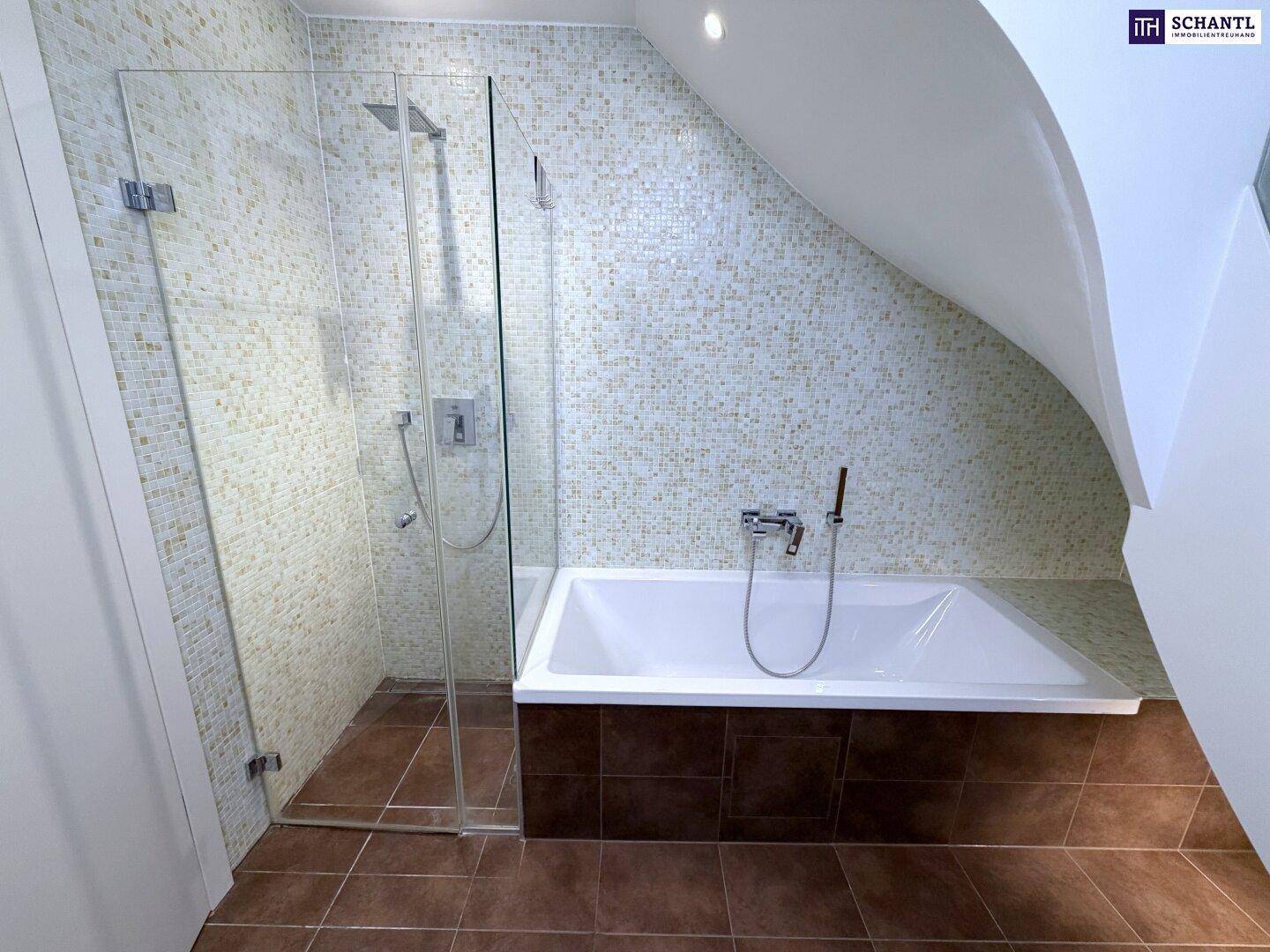 Helles Badezimmer mit Badewanne, Glasdusche und Mosaikfliesen unter einer Dachschräge.