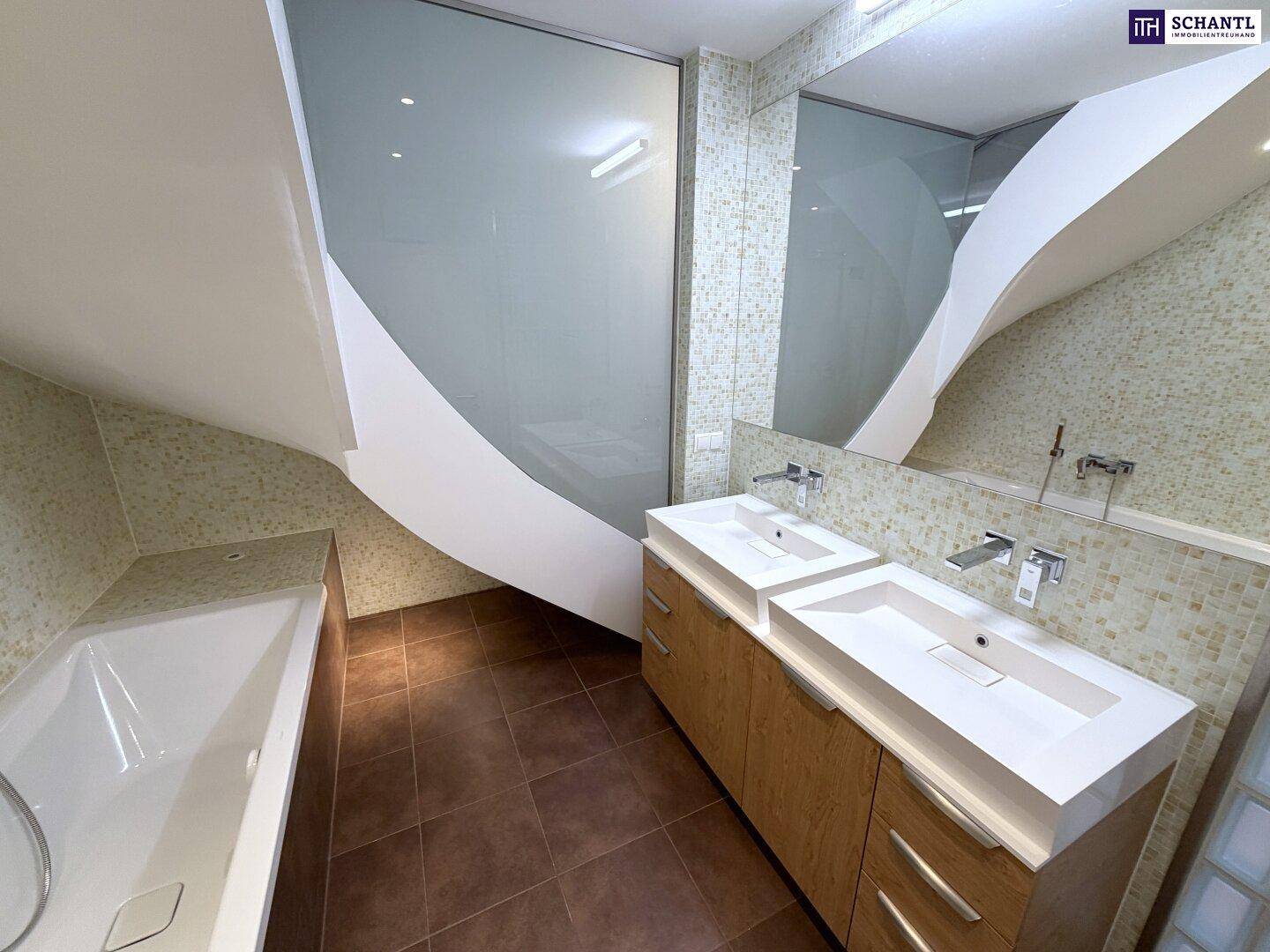 Geräumiges Badezimmer mit Doppelwaschbecken, Badewanne und Holzunterschränken unter Dachschräge.