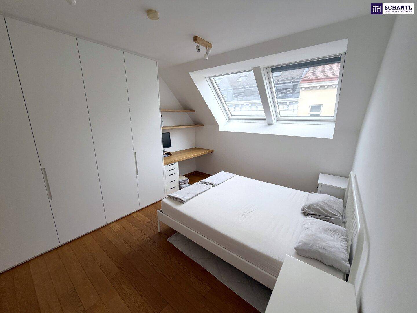 Helles Schlafzimmer mit Dachfenstern, Holzboden und Einbauschränken unter einer Dachschräge.
