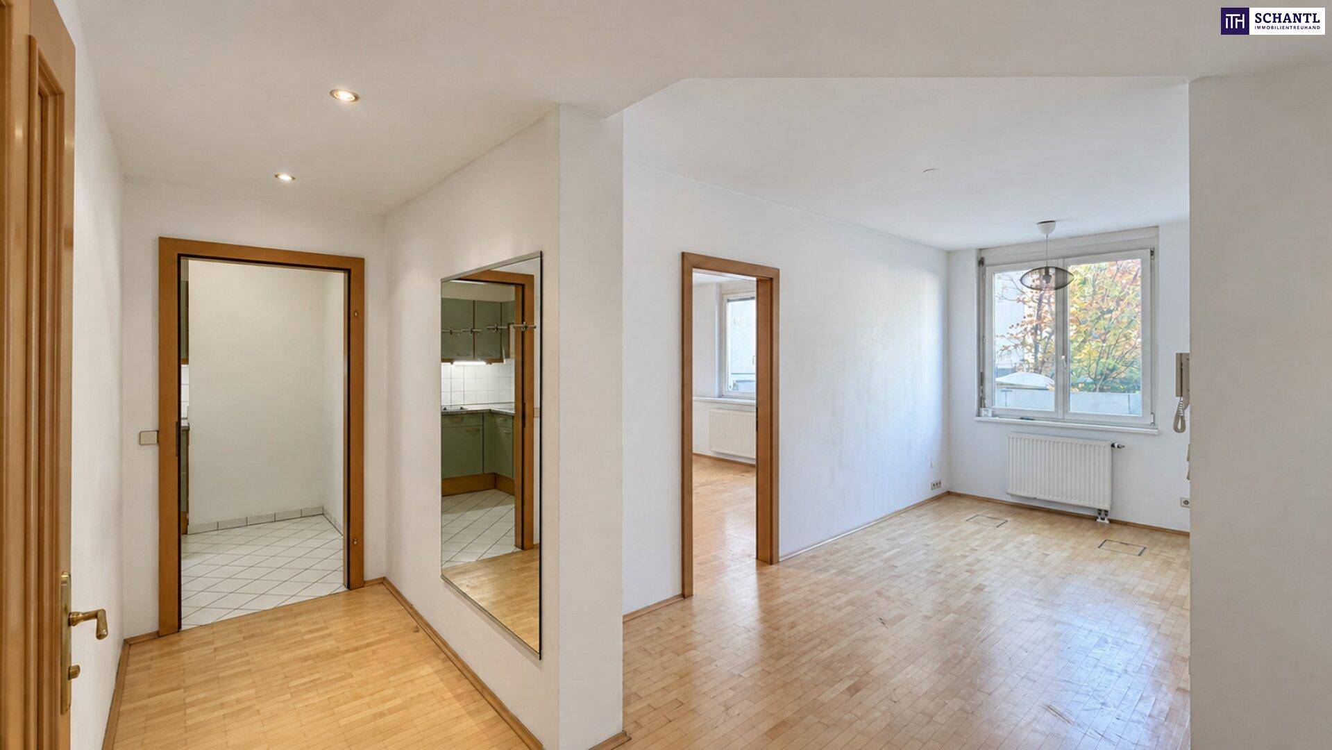 Flur mit Holzboden, großem Spiegel und Blick in angrenzende Zimmer und die Küche.